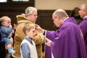 What is Ash Wednesday - priest placing ash on a child's head