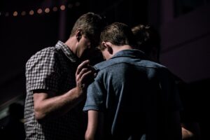 man praying for another man