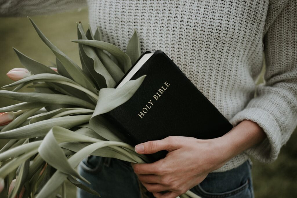 woman holding a Bible and flowers