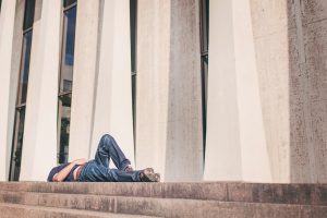 seven deadly sins - man lying down in front of a building