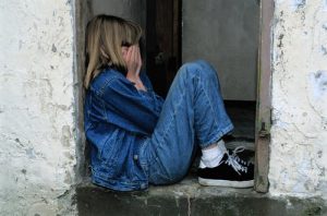 Healing bible verses - a girl covering her face while sitting against a wall