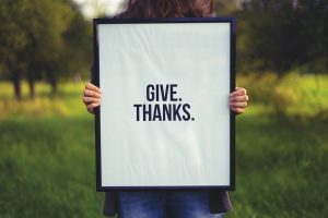 woman holding frame with words give thanks written on it