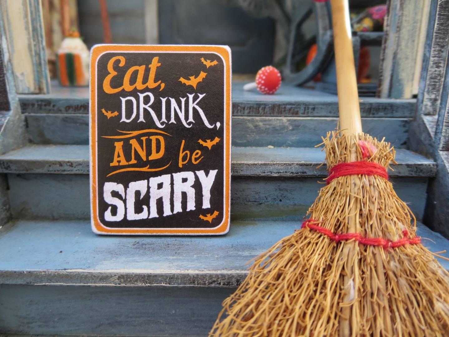 photo of a sign that says "eat drink and be scary" on front porch steps next to a broom, should christians celebrate halloween