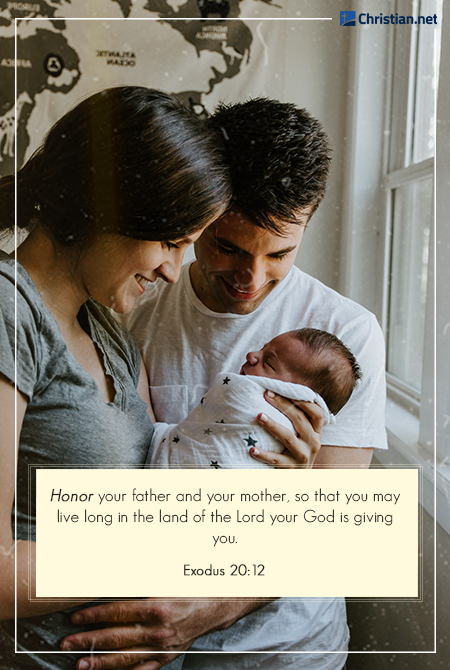 a young couple holding and smiling down at their newborn daughter by the window