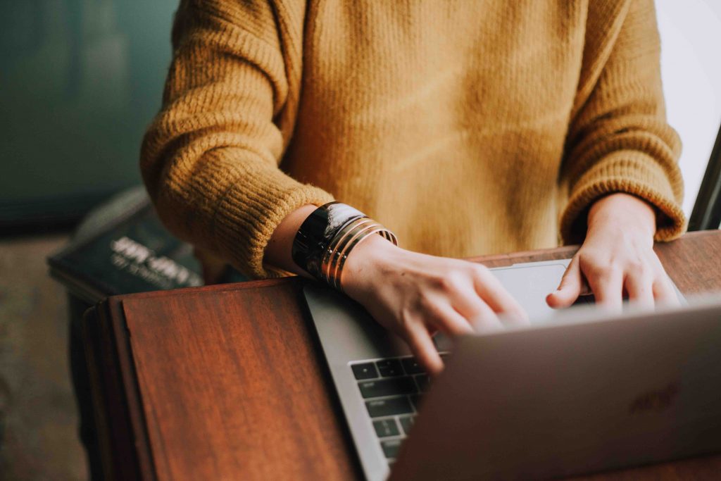 A girl in yellow jumpers typing away on her laptop