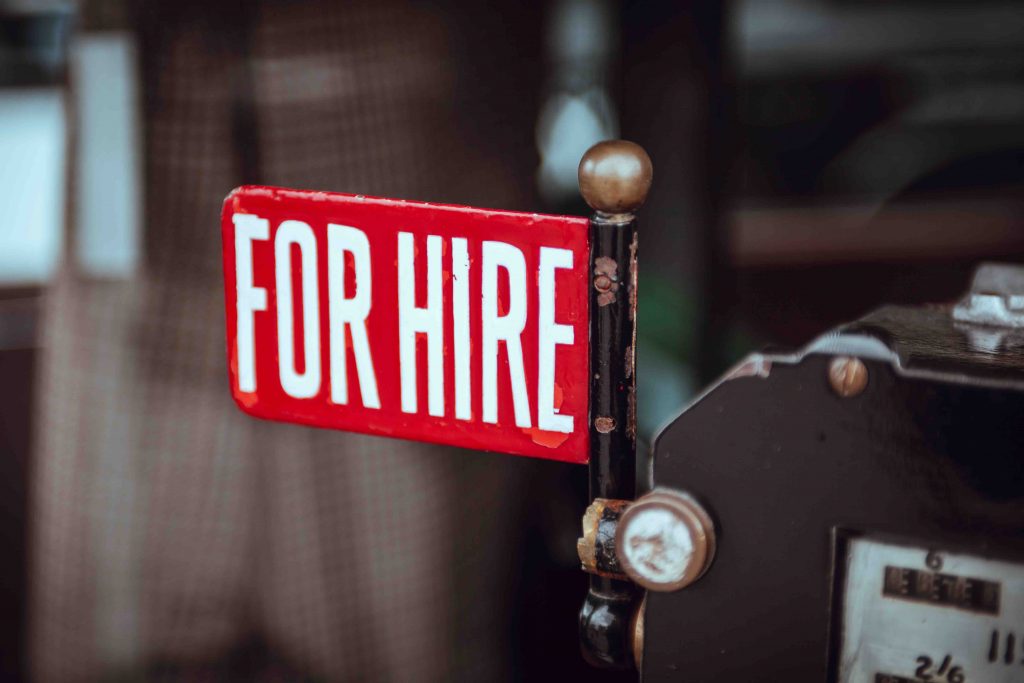 A selective focus shot of a red "for hire" sign 
