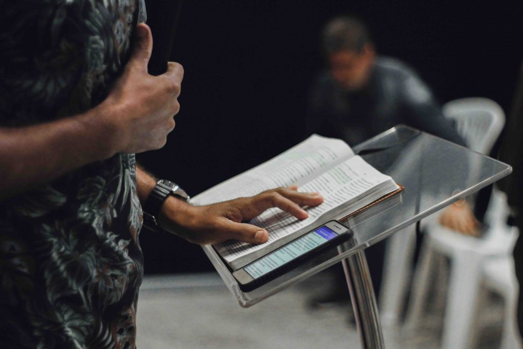 A pastor preaching on the pulpit with his Bible and phone