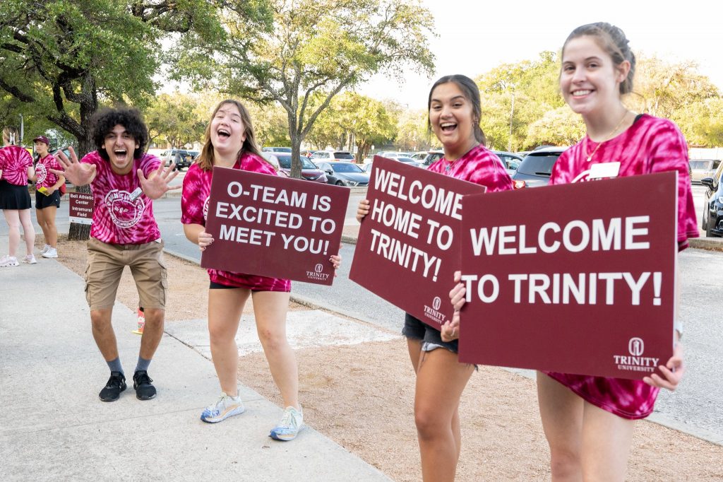 a group of girls holding up sign boards to welcome people to the college open house day 