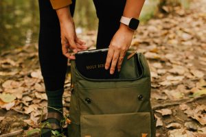 a women putting a bible into her backpack
